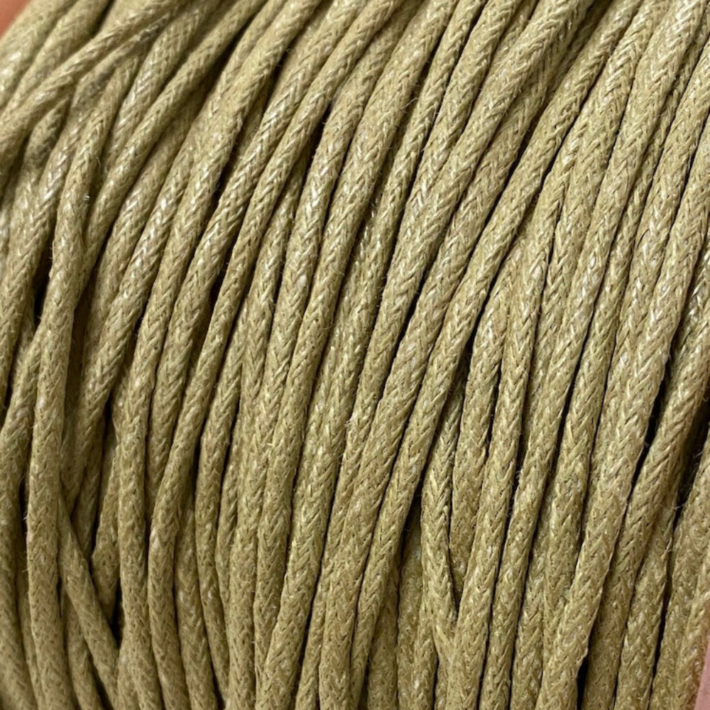 A spool of natural beige waxed cotton cord used for crafting and jewelry making.