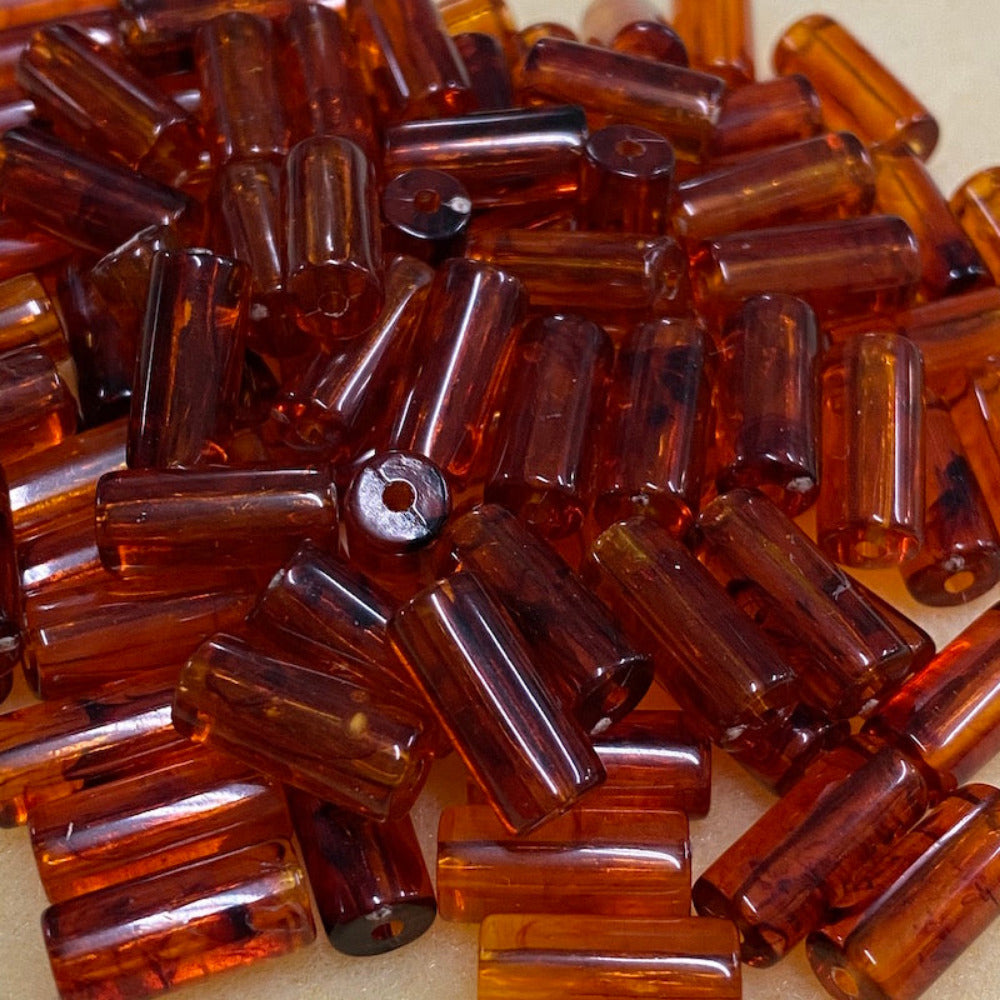a group of transparent amber colour beads displayed on a cream surface with visible holes for stringing jewelry and creating craft