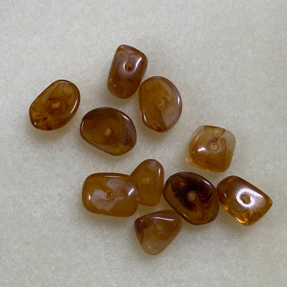 brown jasper gemstone look acrylic beads with visible threading holes for crafting jewelry on a white background against a ruler for scale