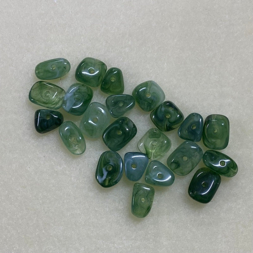 Jade green gemstone style acrylic beads with visible threading holes for crafting jewelry on a white background