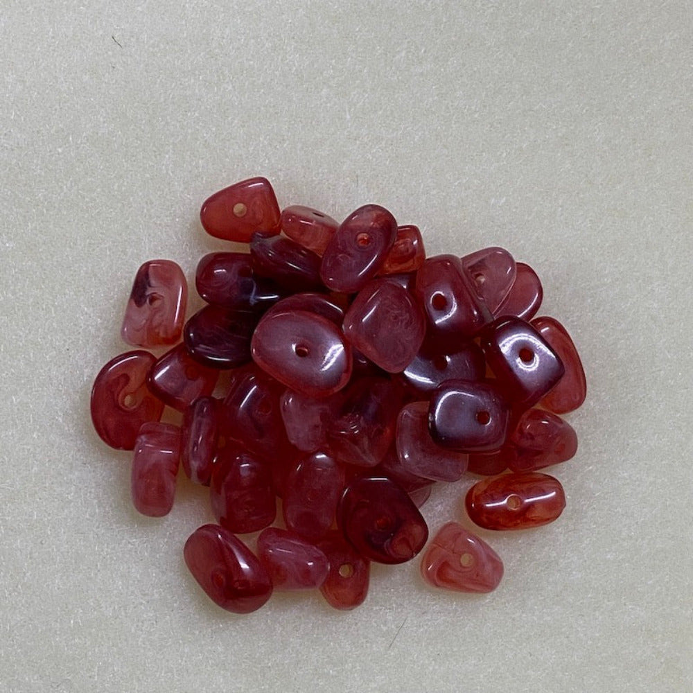 ruby look acrylic beads with visible threading holes for crafting jewelry on a white background