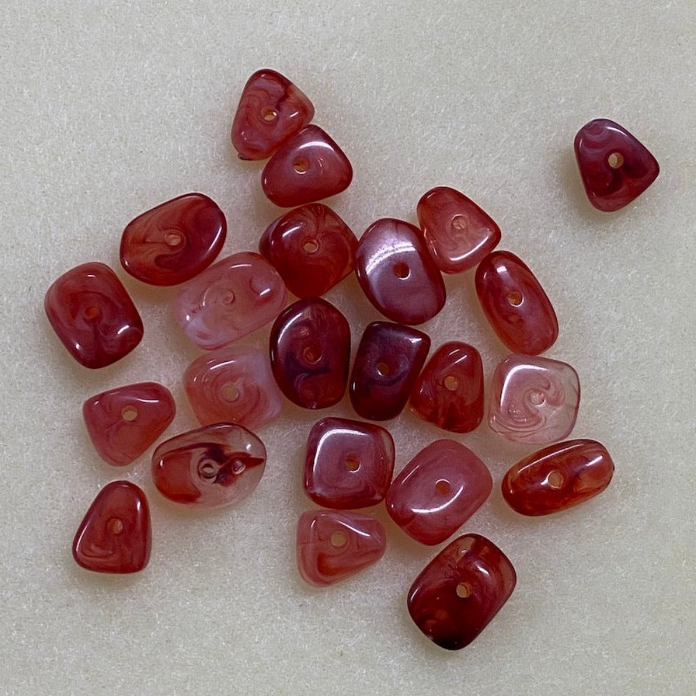 ruby look acrylic beads with visible threading holes for crafting jewelry on a white background