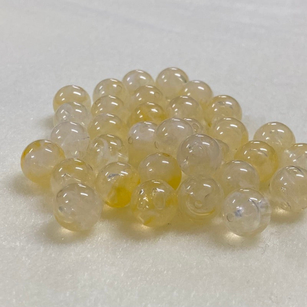 Citrine yellow gemstone style acrylic beads with visible threading holes for crafting jewelry on a white background
