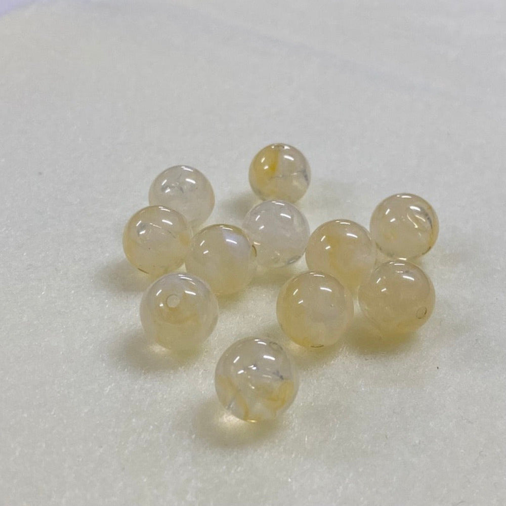 Citrine yellow gemstone style acrylic beads with visible threading holes for crafting jewelry on a white background