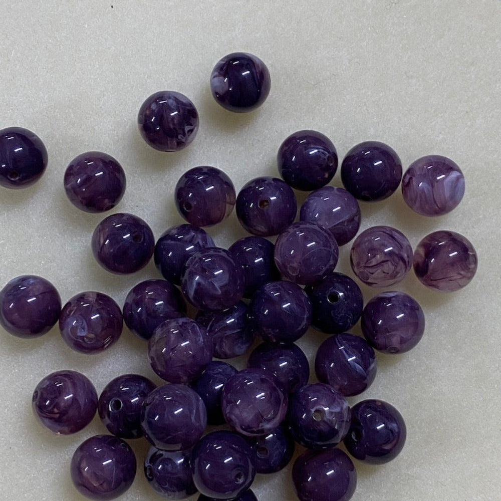 Amethyst purple gemstone style acrylic beads resembling real gemstones, with visible threading holes for crafting jewelry on a white background, used for crafting and jewelry making.