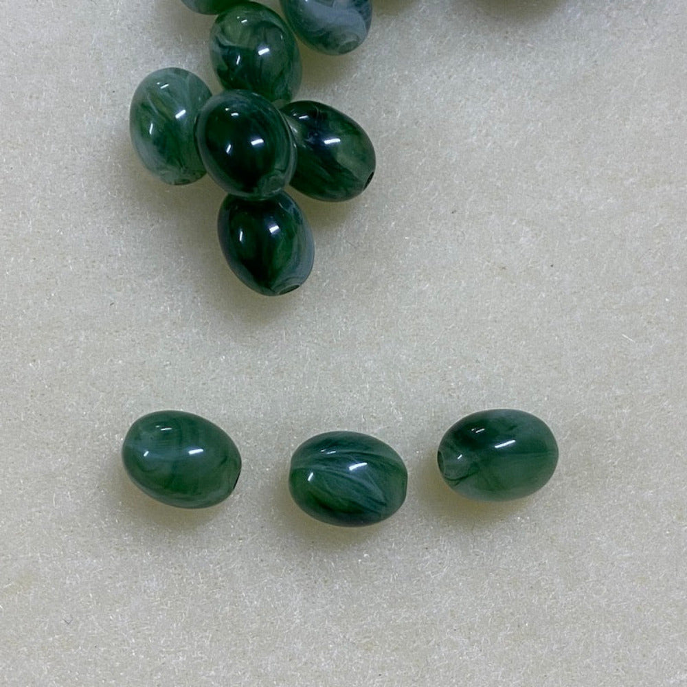 Jade green gemstone style acrylic beads with visible threading holes for crafting jewelry on a white background