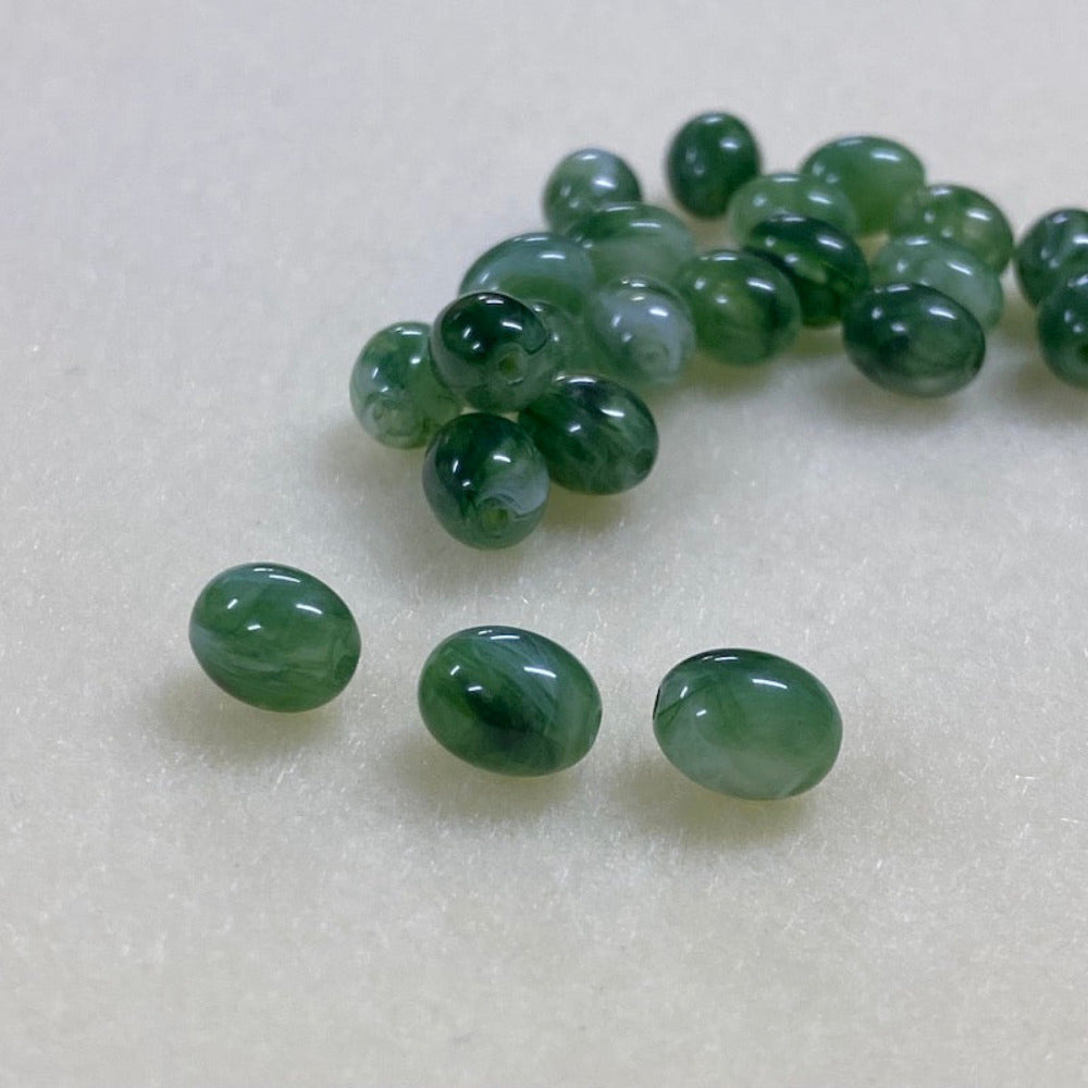 Jade green gemstone style acrylic beads with visible threading holes for crafting jewelry on a white background