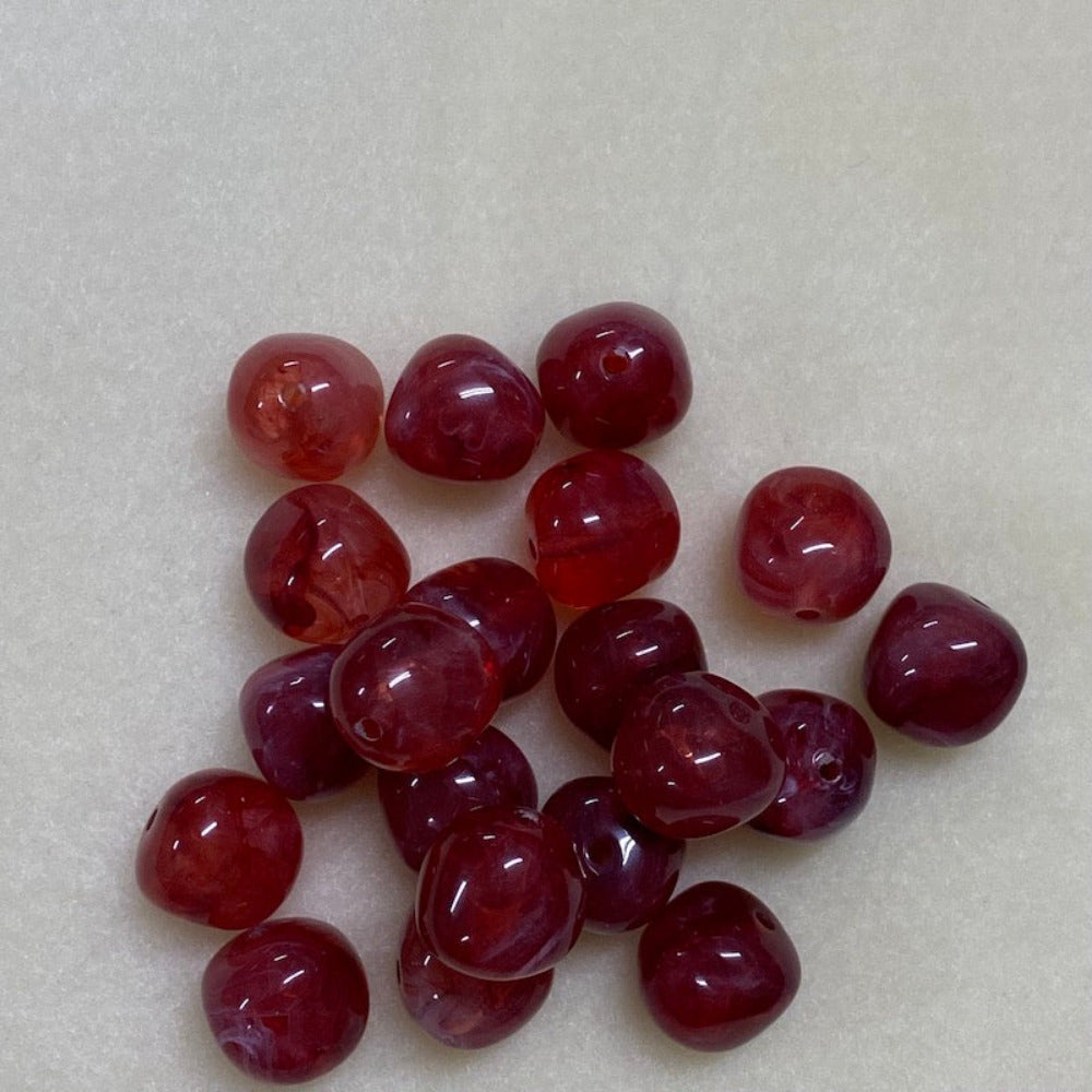 ruby look acrylic beads with visible threading holes for crafting jewelry on a white background