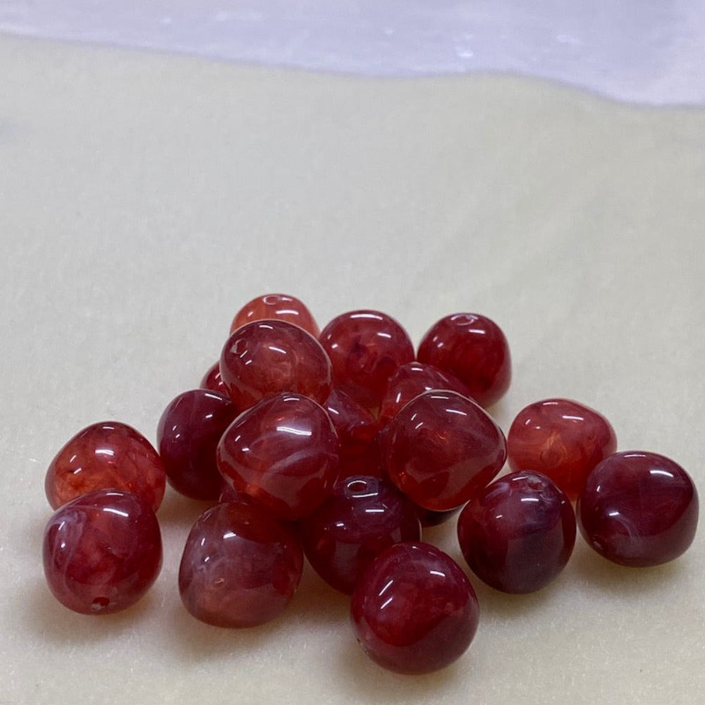 ruby look acrylic beads with visible threading holes for crafting jewelry on a white background