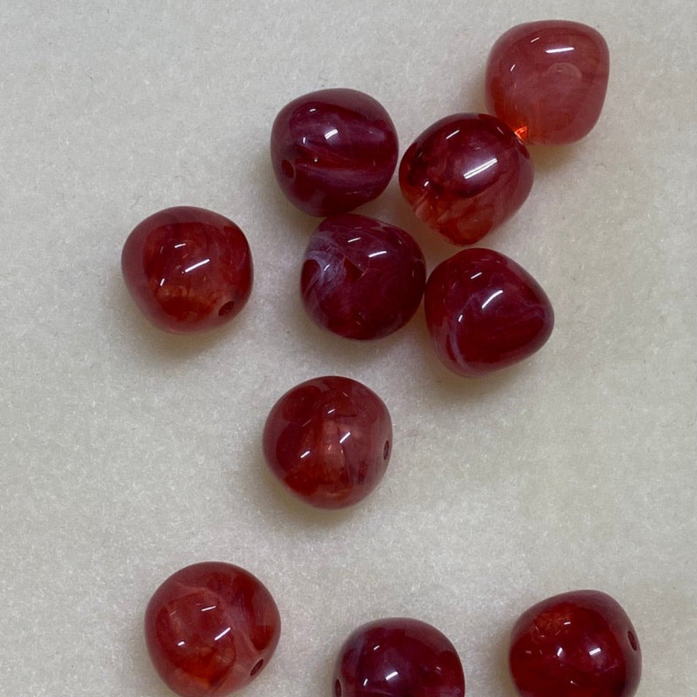ruby look acrylic beads with visible threading holes for crafting jewelry on a white background
