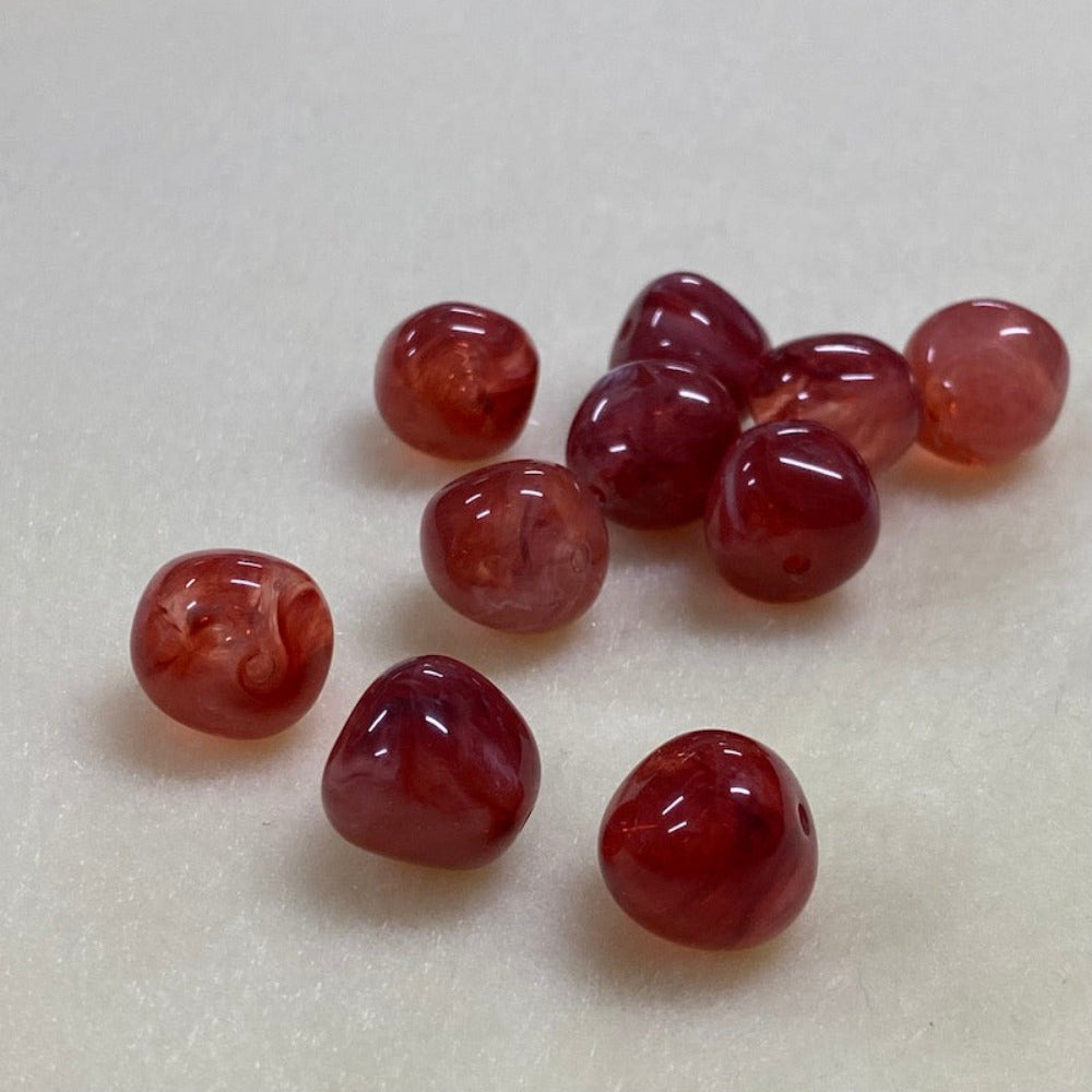 ruby look acrylic beads with visible threading holes for crafting jewelry on a white background