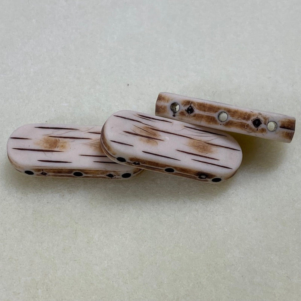 bone look flat beads with 3 threading holes shown clearly on a cream background