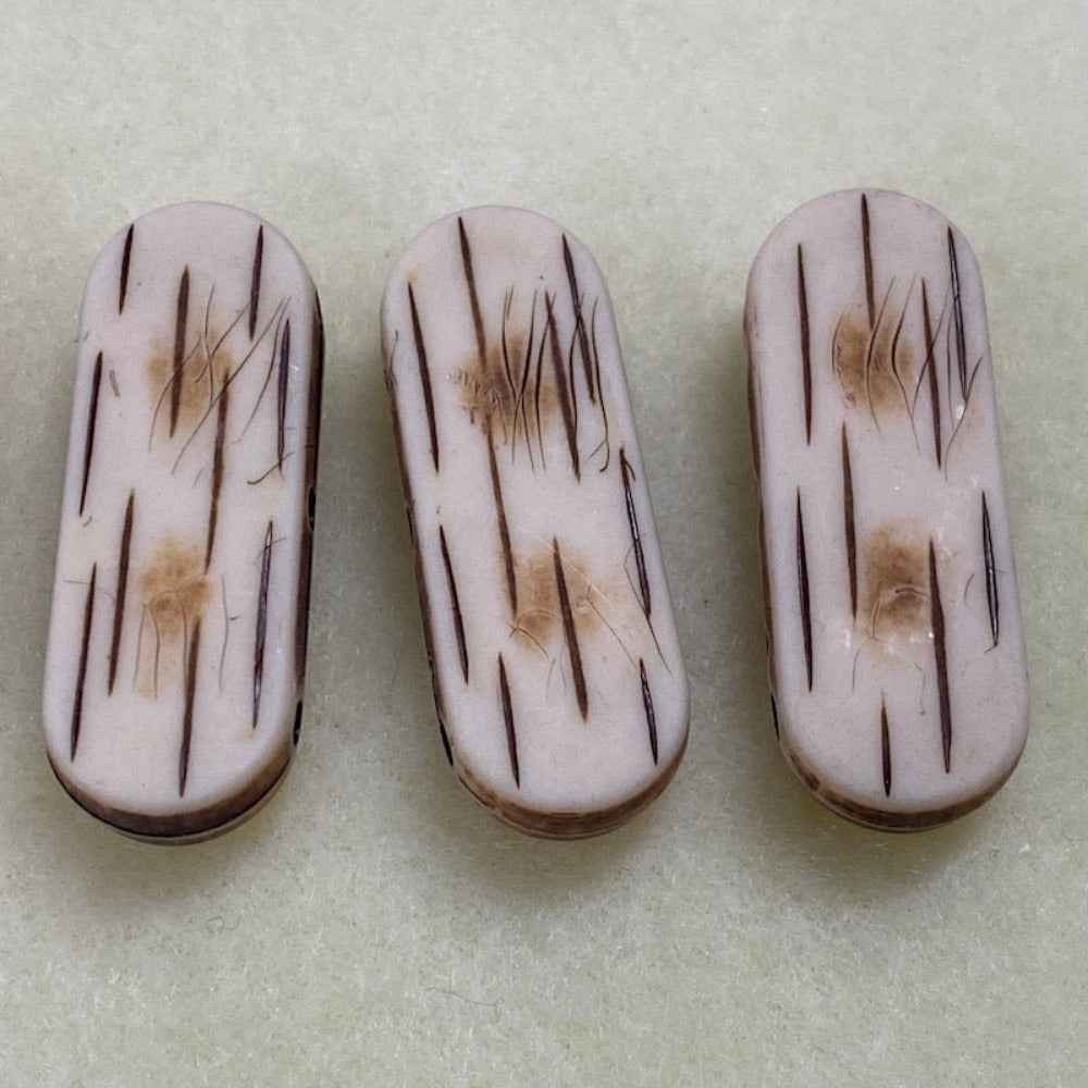 flat bone look beads with visible black lines and brown patterns