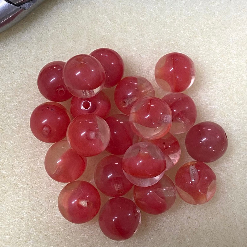 close up photo of a group of tomato red givre glass beads on a brown surface