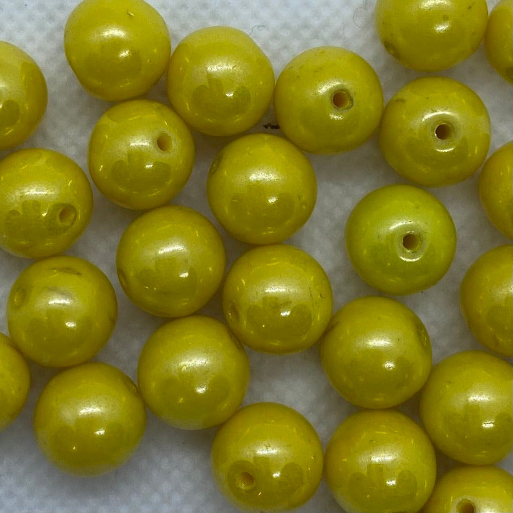 Yellow lustrous round beads on a white surface