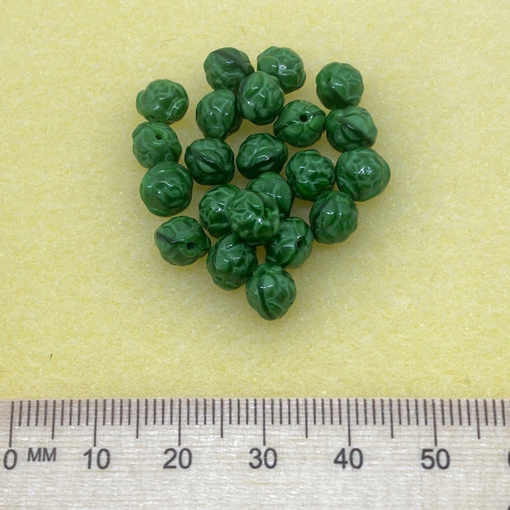 rose shape beads with patterning in a bunch on a grey background showing clear threading holes for jewelry making with a ruler to show scale