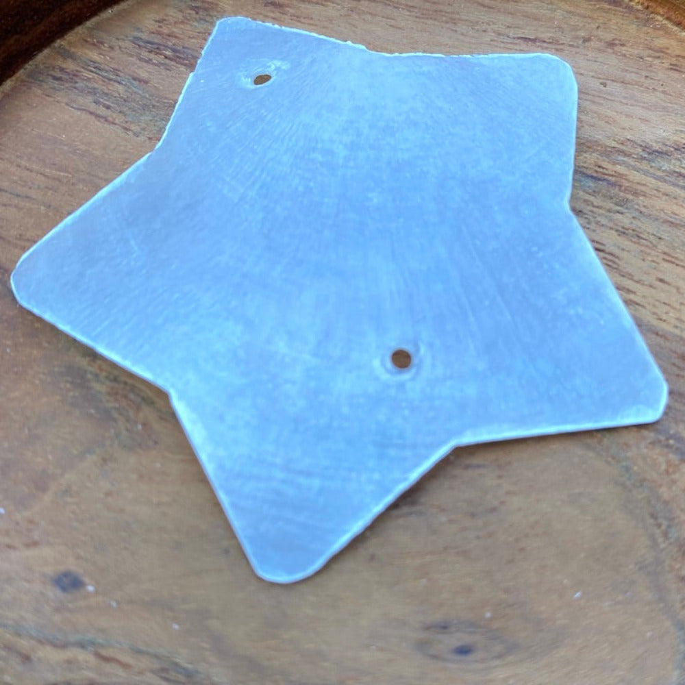a white star shaped capiz shell on a wood background for the purpose of making decor, craft and hanging decorations