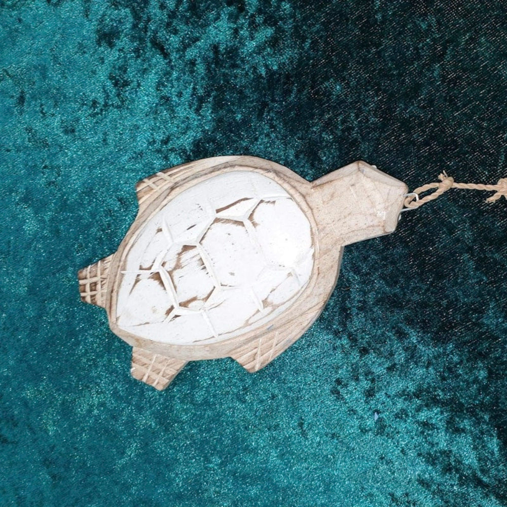 Wood turtle decoration on a teal background strung on seagrass string