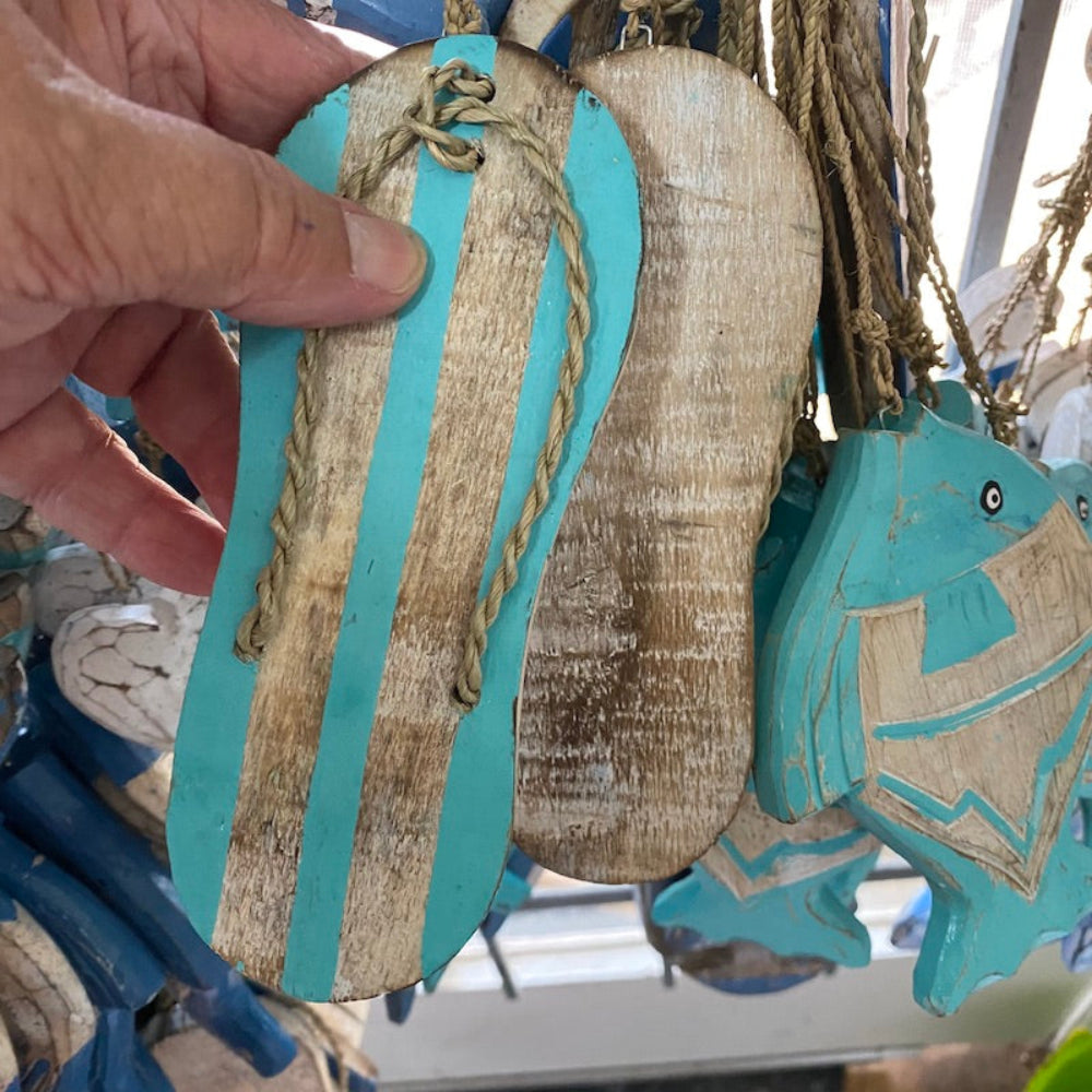 Wood blue and white thong shapes decorations in a shop window also showing fish in the background