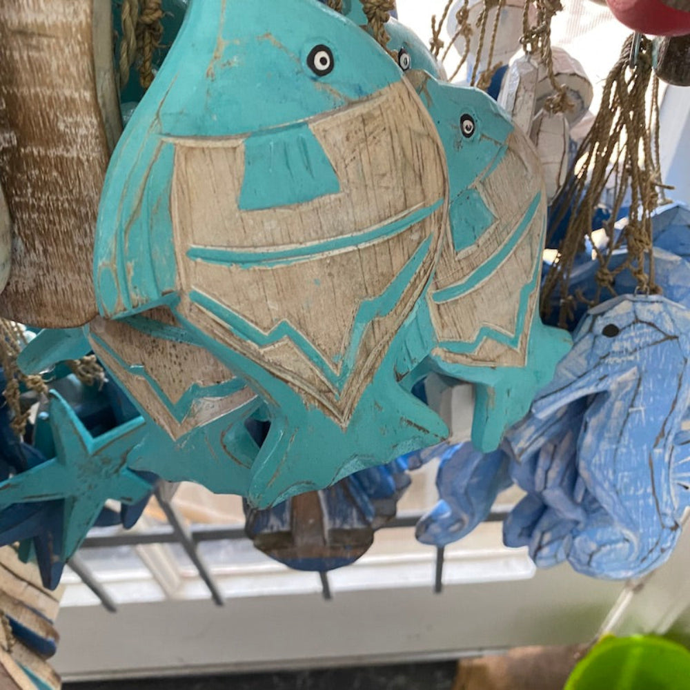 Wood blue and white flat fish decorations in a shop window also showing seahorse and star shapes