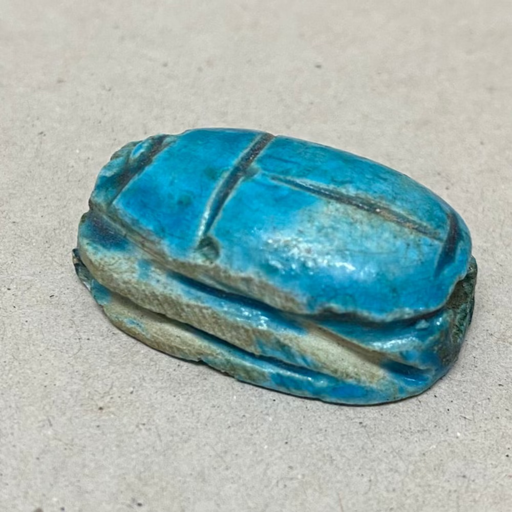 One vintage blue clay handmade scarab bead on a grey surface