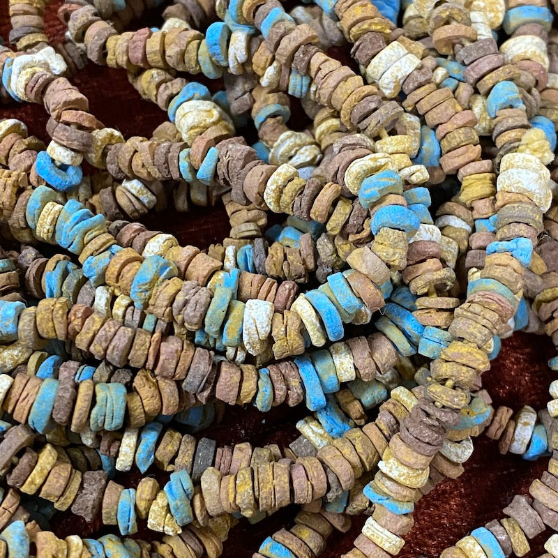 A collection of colored faience beads arranged in a loop, with varying shapes and textures.