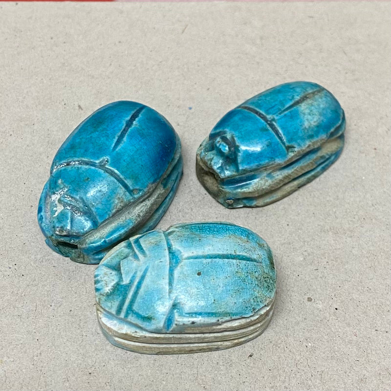 A set of three vintage Egyptian scarab beads in blue color, displaying various sizes and details.