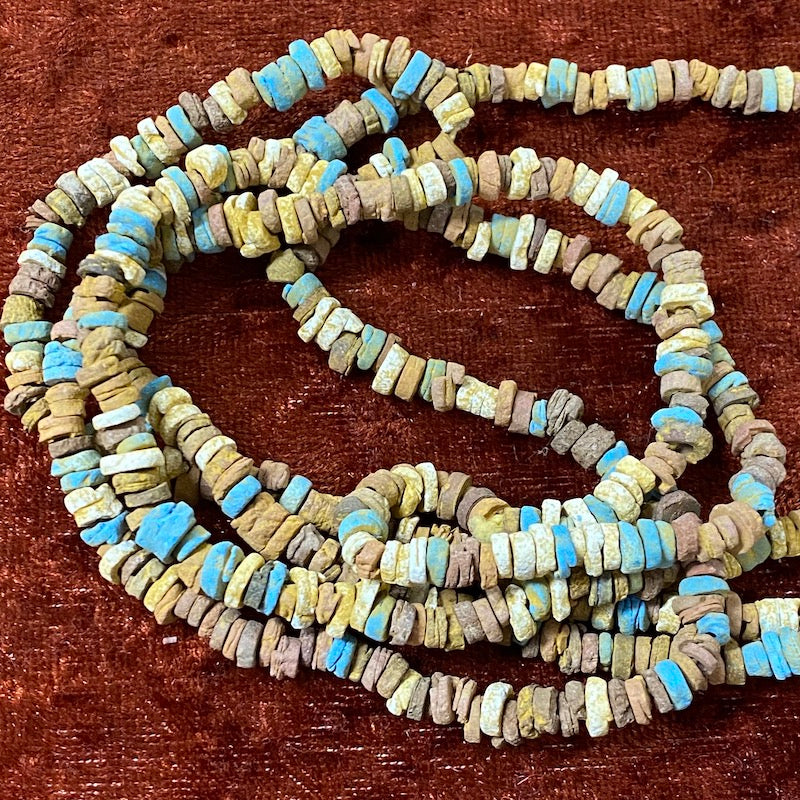 A collection of colored faience beads arranged in a loop, with varying shapes and textures.