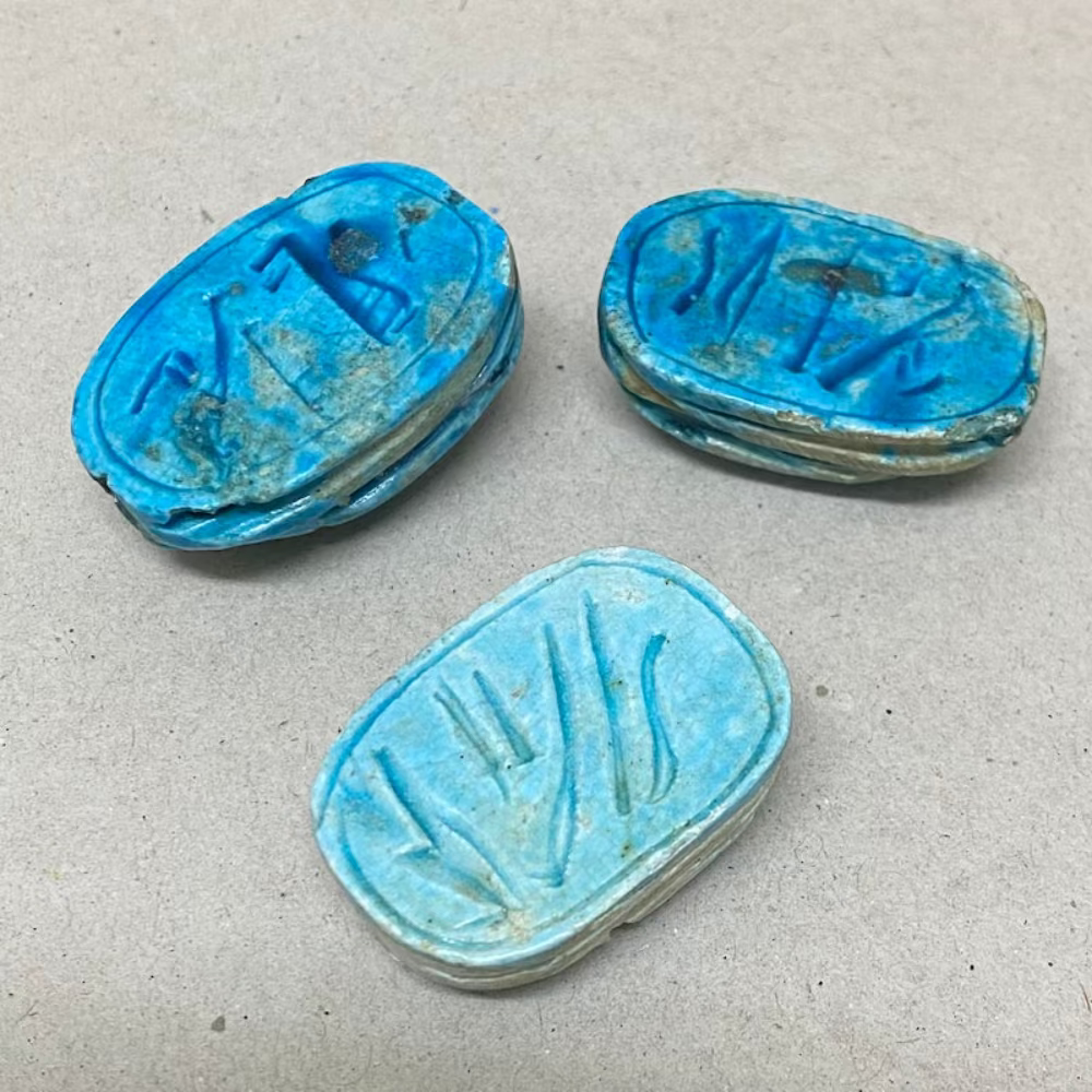 A set of three vintage Egyptian scarab beads in blue color, displaying the reverse side in various sizes and details.