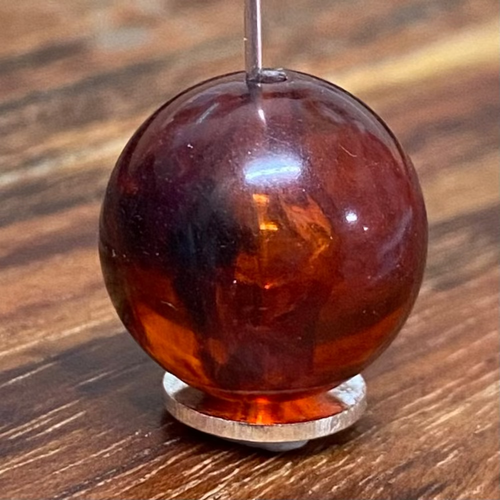 one round transparent amber colour beads displayed on a wood surface with visible holes for stringing jewelry and creating craft