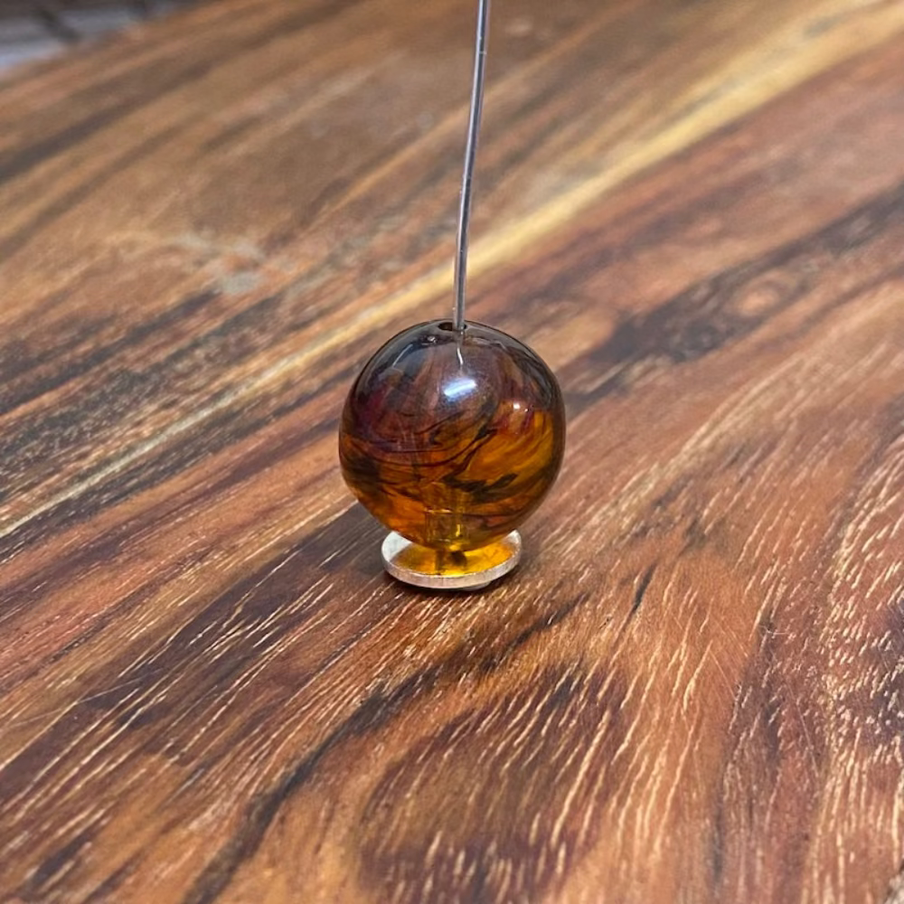 one honey-colored amber beads with black markings, displayed on a wooden surface