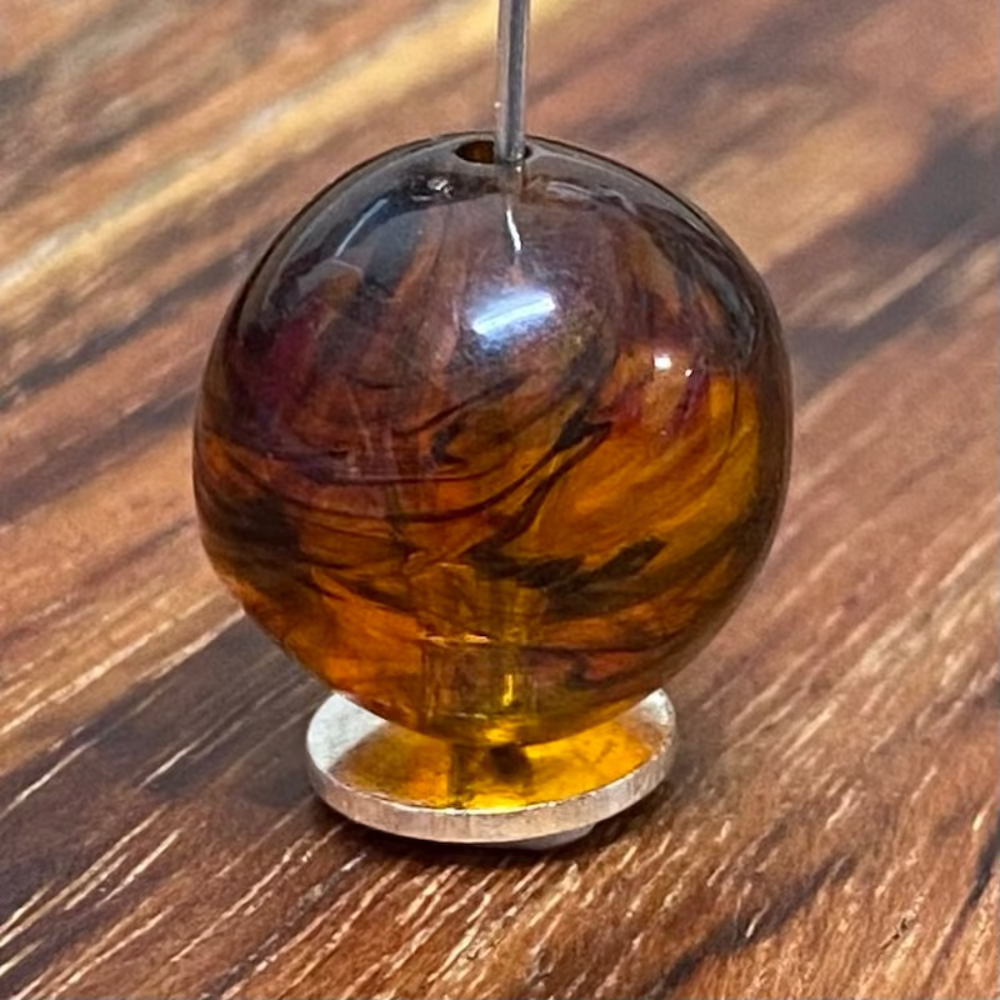One honey-colored amber beads with black markings, displayed on a wooden surface