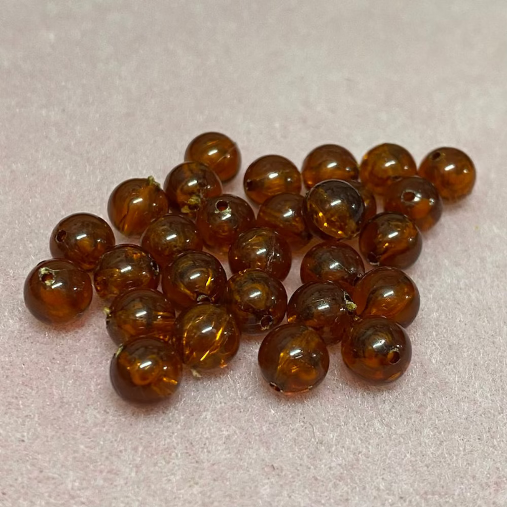 transparent amber beads in a group with a pink surface in the background