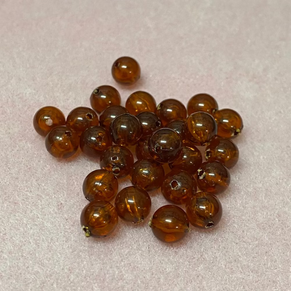 transparent amber beads with a pink surface in the background