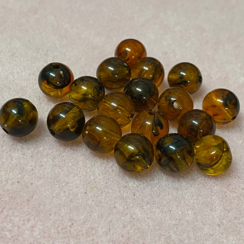 transparent amber beads in a group with a pink surface in the background
