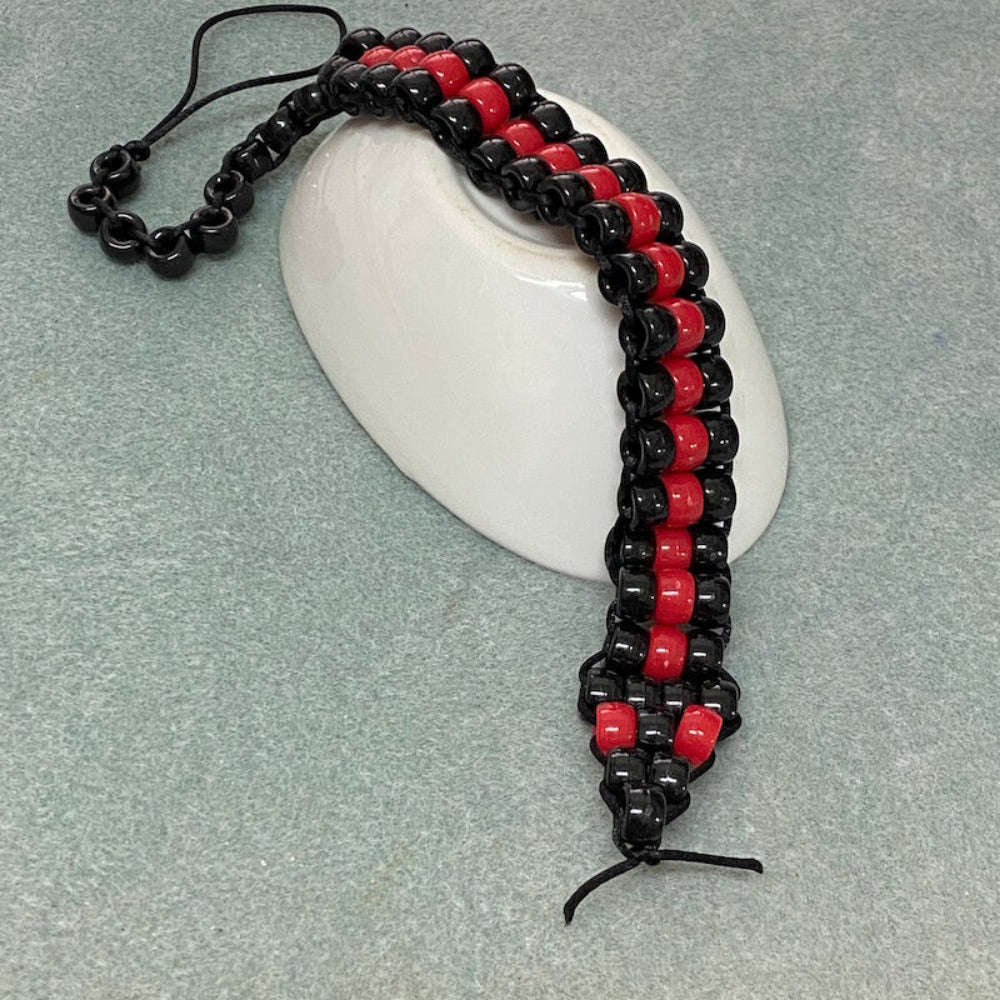 beaded red belly black snake toy made at Bead Shack snakes & lizard birthday party draped over an upturned white bowl on a grey background