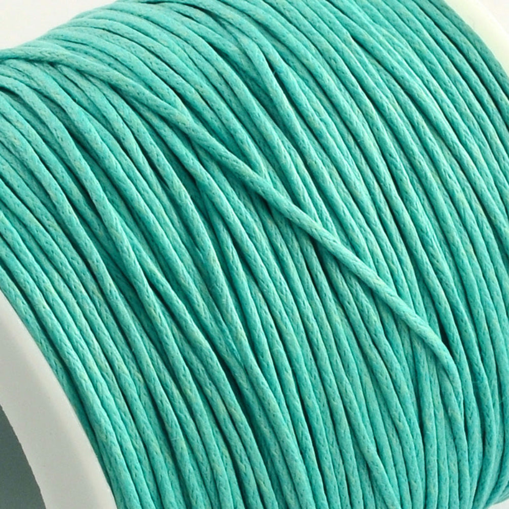 A spool of aqua turquoise wax cotton cord used for crafting and jewelry making.