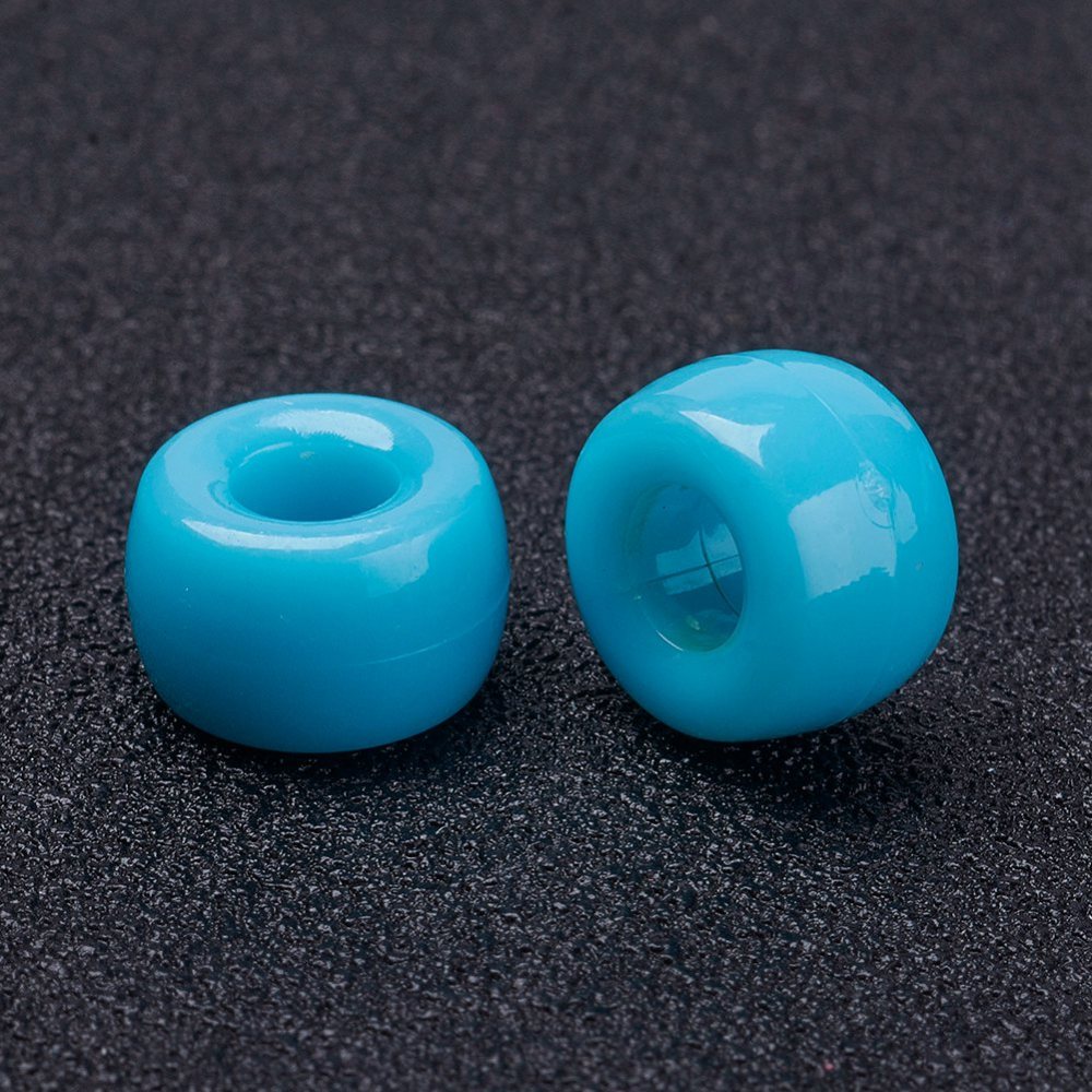 close up of 2 large holed acrylic beads used for craft and jewelry making on a black background