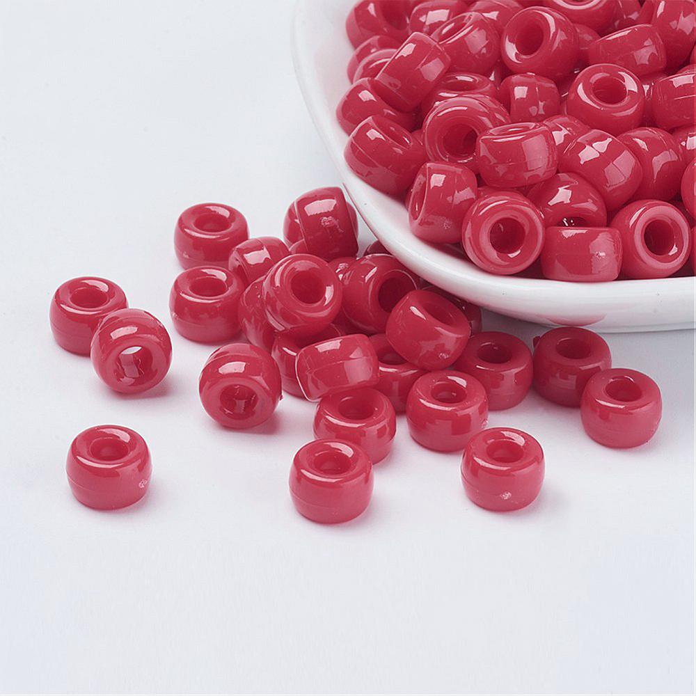 a white bowl of large holed red pony beads spilling over onto a white surface with visible holes for stringing and craft making