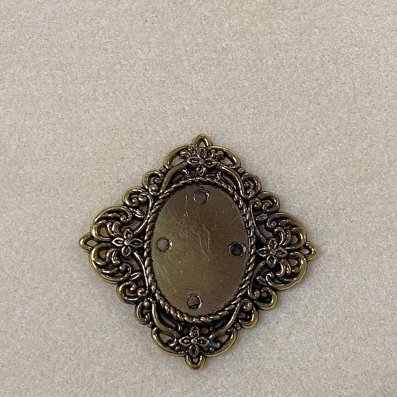 a vintage fancy flat cabochon fitting with intricate scrolling design around the outside with little flowers on the corners