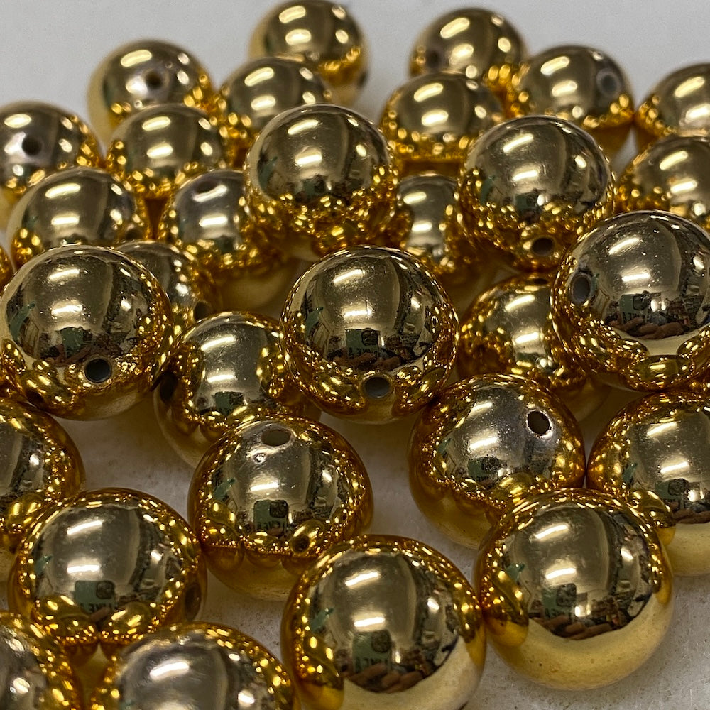 An image of gold shiny beads with visible threading holes which are great for Christmas and party decorations as well as beading jewellery and craft items