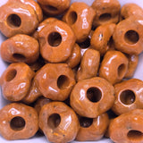 Close-up of orange beads with holes on a white background