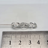 Clear glass beads on a metal rod with a ruler for scale on a white background