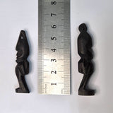Two black african vintage wooden figures on a white background next to a ruler to show scale