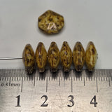 Brown beads with a hexagonal shape on a ruler for scale
