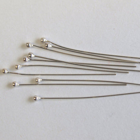 Set of metal pins with silver heads on a light gray background