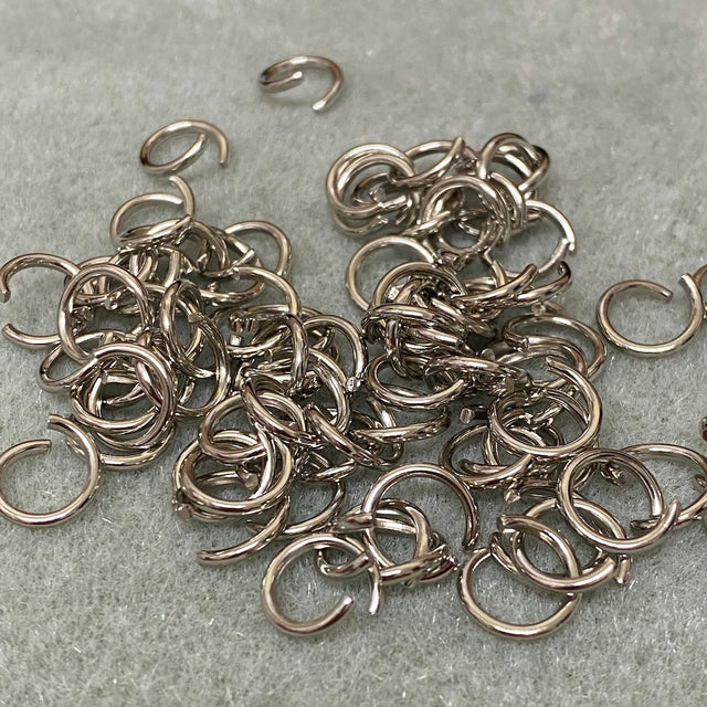 Collection of silver jump rings on a gray surface