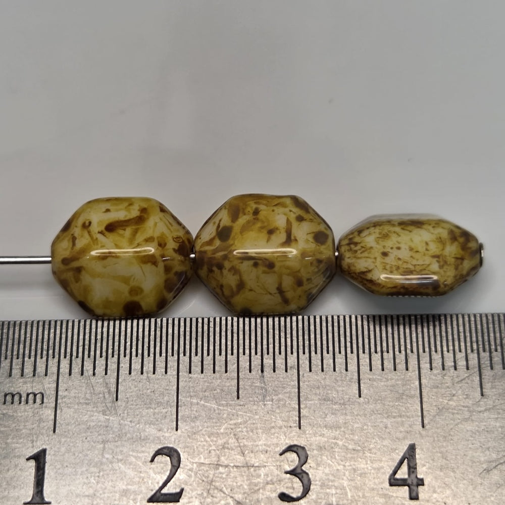 Three brown beads on a ruler for size reference