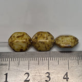Three brown beads on a ruler for size reference