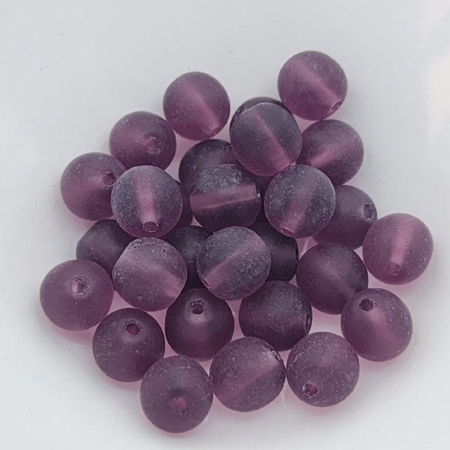 A collection of purple glass beads showing threading holes